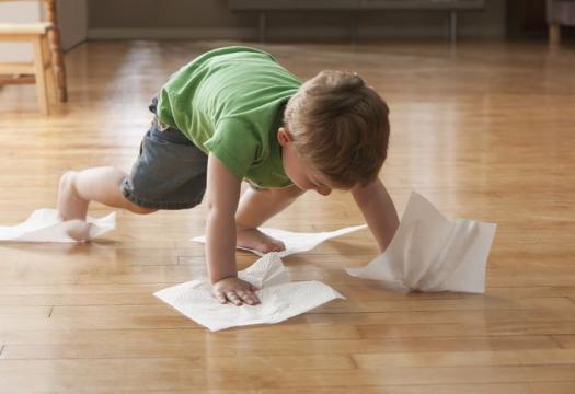 Child cleaning floor with paper towels.
