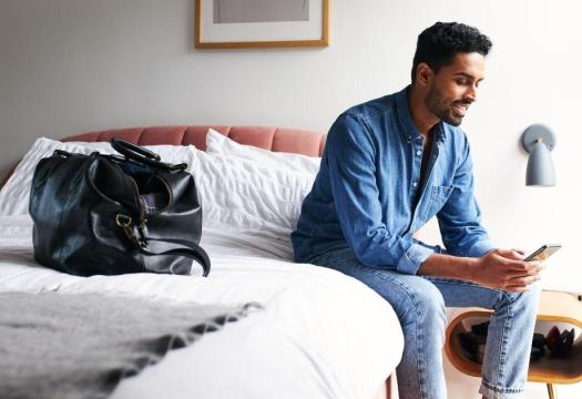 Man sitting on bed in guestroom | Merry Maids