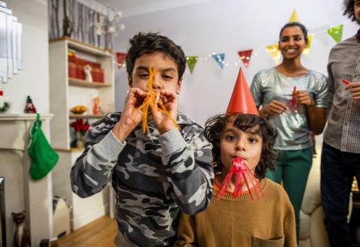 Family celebrating the new year. Kids using whilst blowing streamers and counting down to the new year | Merry Maids