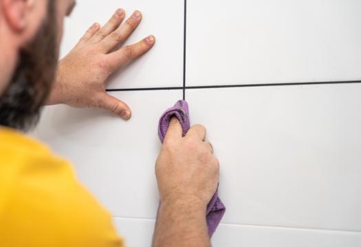 Man wipes tile joints after painting it with black acrylic marker | Merry Maids