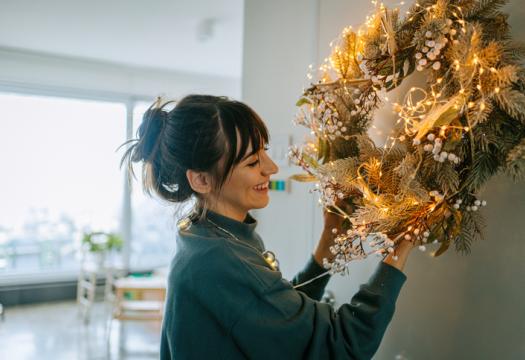 Young woman hanging a wreath on the living room wall | Merry Maids