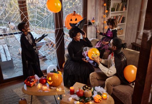 Happy African American family in costumes talking during a Halloween celebration at home | Merry Maids