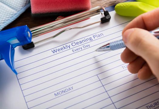Close-up Of Person Hand Filling Weekly Cleaning Plan Form | Merry Maids