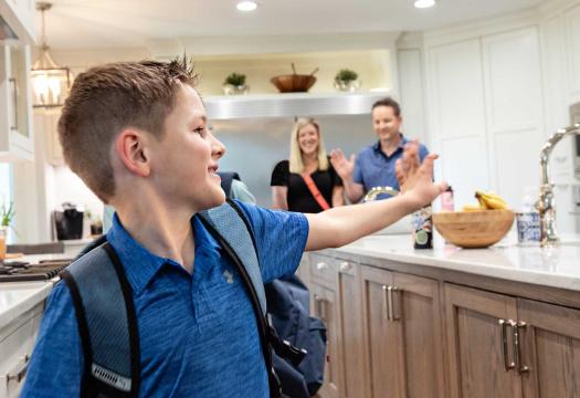 Boy waving to family in kitchen